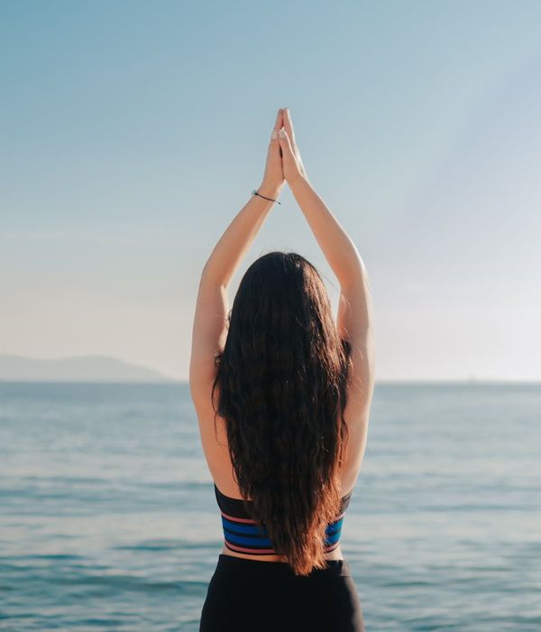 Woman meditating peacefully in a yoga pose at sunrise, surrounded by calm energy